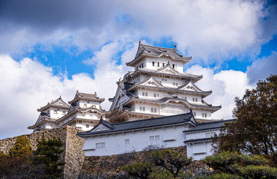 Himeji Castle stands tall against bright blue skies with clouds in Hygo Prefecture, Japan