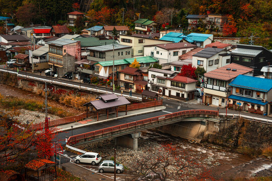 Vibrant autumn scene over Yamanouchi town with traditional houses, bridges, and colorful trees in Nagano Prefecture, Japan
