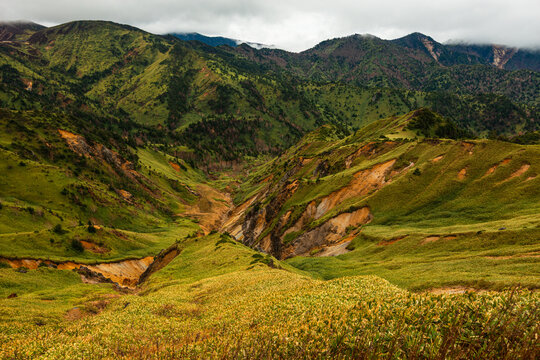 Colorful volcanic landscape shows rugged terrain shaped by geothermal activity and alpine flora in Japan's Nagano Prefecture