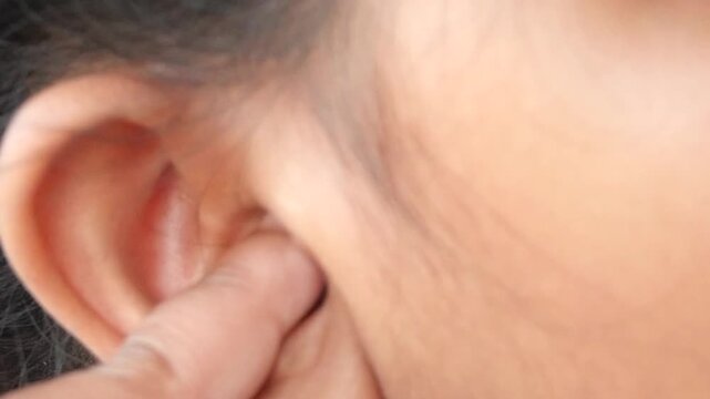 Close up of finger scratching itchy ear canal area for relief in slow motion clip