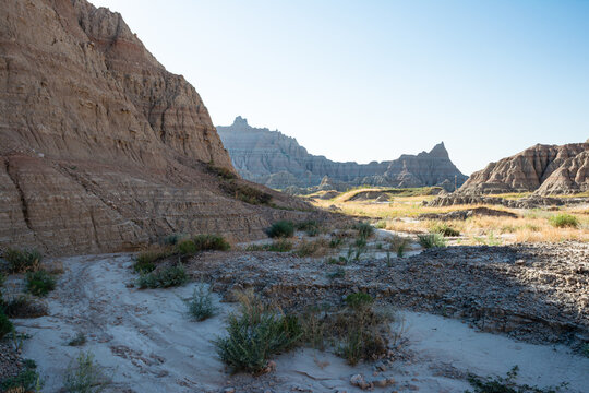 Wide desert valley framed by badlands formations in Badlands National Park in South Dakota USA with clear blue sky overhead