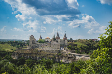 Obraz premium Ancient stone fortress perched on a cliff overlooking a lush green valley