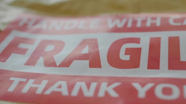 Fragile handle with care sticker on shipping package with dynamic camera motion revealing red and white warning label