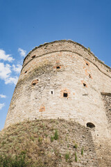 Ancient stone fortress tower against a bright blue sky with scattered clouds © Constantin