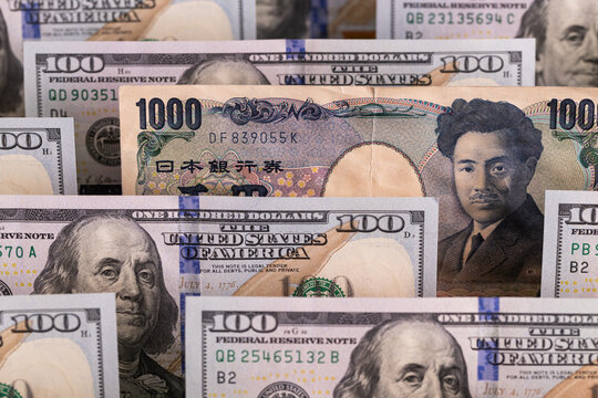 Japanese 1000 yen banknote standing out among rows of US hundred dollar bills