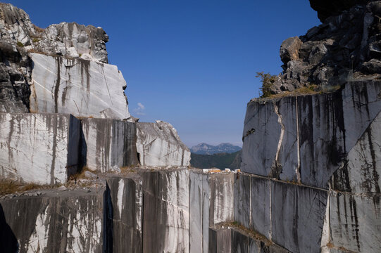 Abandoned marble quarry with towering rock walls beneath clear blue sky