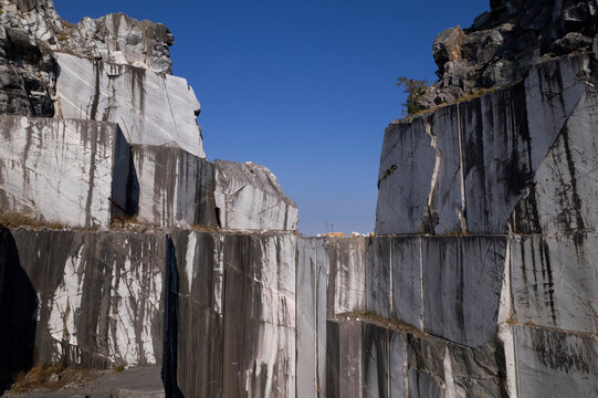 Abandoned marble quarry with towering rock walls beneath clear blue sky
