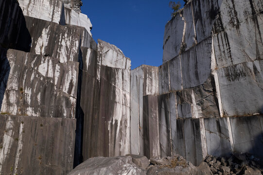 Abandoned marble quarry with towering rock walls beneath clear blue sky