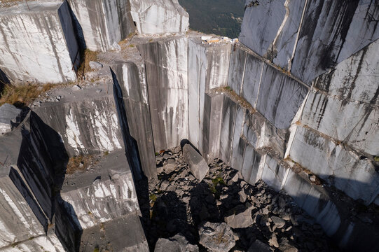Abandoned marble quarry with towering rock walls beneath clear blue sky
