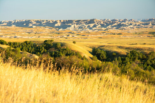 Expansive prairie rolls into eroded ridges and badlands under partly cloudy skies in South Dakota