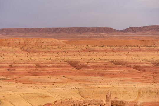 Arid hills and layered desert terrain in southern Morocco on a dry day with overcast skies