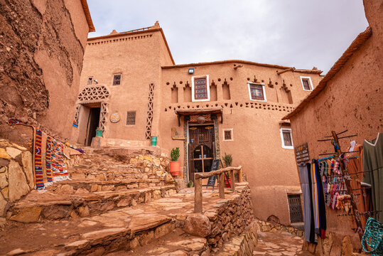 Stone steps lead to a kasbah home showcasing traditional Berber design in Ait Ben Haddou, Morocco with local crafts displayed nearby