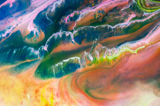 Colorful abstract patterns are created with paint on a canvas in a studio