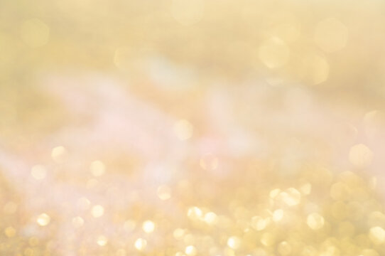 Golden light shines in a blurry background with flecks of light spread across the scene