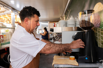 Fototapeta premium Barista grinding coffee beans preparing fresh coffee drink