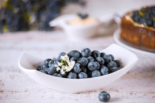 Bowl of fresh blueberries with dessert in background at kitchen table