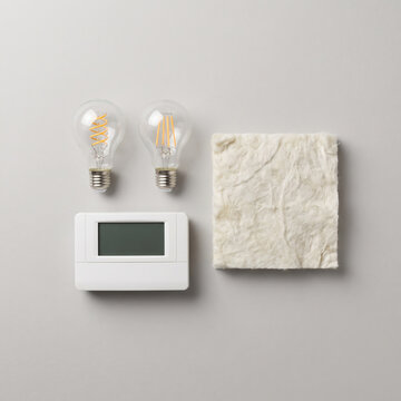 LED bulbs with programmable thermostat and insulation batt swatch on flat lay surface