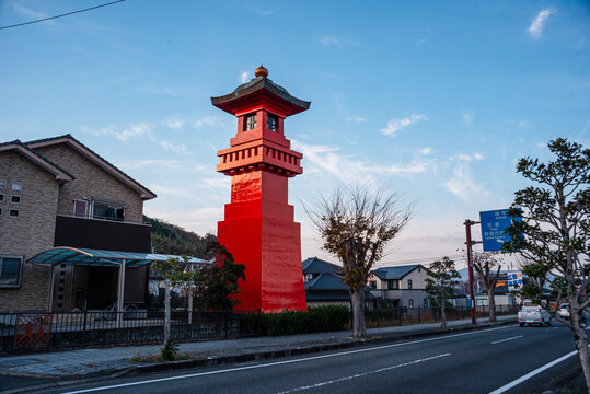 Red lantern tower stands beside roadside near local shrine in Kashima, Japan