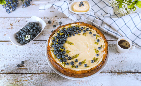 Blueberry cheesecake on table with dessert toppings fresh berries in kitchen setting