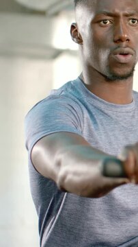 Vertical video: Gripping handle, man doing seated rowing at gym for training, gray tee shorts watch