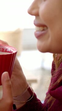 Vertical video: Smiling woman in maroon sharing red cup at window, steadying as child reaches