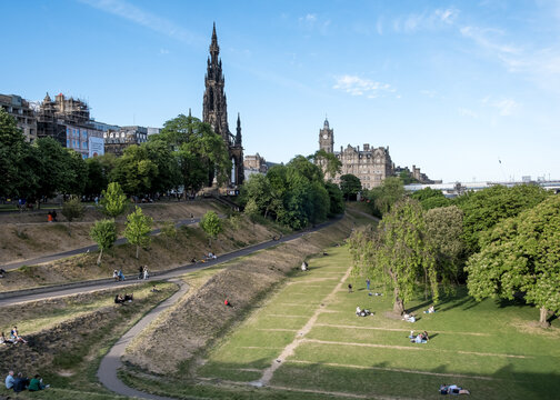 Visitors enjoy East Princes Street Gardens in Edinburgh with views of monuments and walking paths on a clear day in Scotland