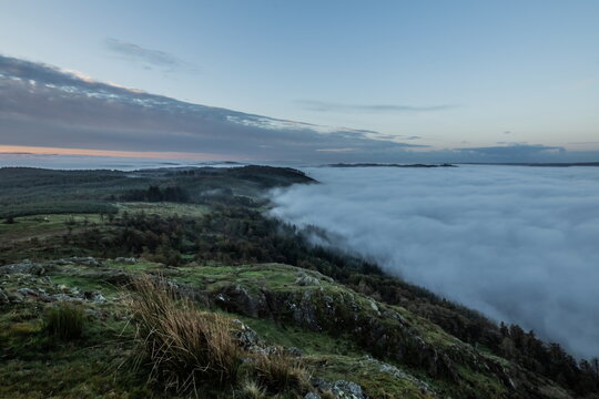 View from Gummers How shows cloud inversion above Lake Windermere at dawn with rolling mist across the landscape in United Kingdom