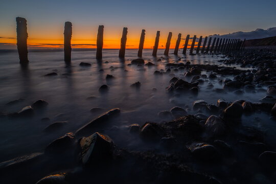 Sunset view from sea defences with wooden posts along the shore at South Walney in the United Kingdom