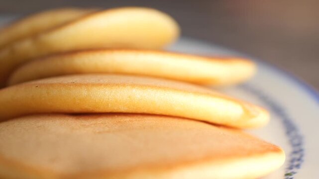 Close up of golden brown pancakes stacked on a plate with a blue rim