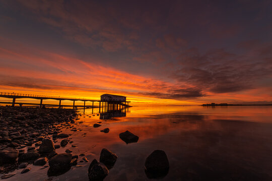 Stunning sunrise at lifeboat station with colorful sky reflecting in water near Piel Island in Cumbria