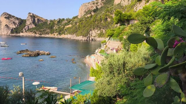 Aerial-like view of La Perla beach in Nerano, Amalfi Coast. Stunning descent down the stairs towards the crystal clear turquoise sea and pebbled shore on a sunny summer day