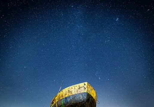 Cloudy skies above the derelict trawler Vita Nova in Cumbria with stars visible in the night sky