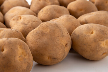 Fototapeta premium Freshly harvested potatoes with soil on white background, closeup food stock photo