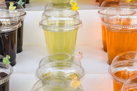 Plastic cups with colorful drinks and small duck figures