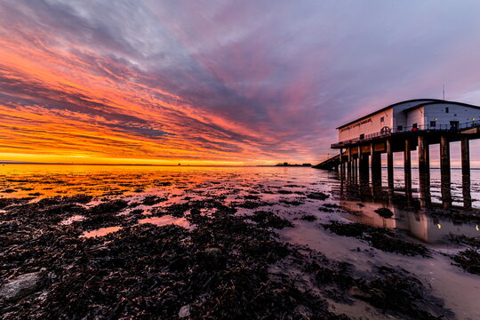Sunrise over Roa Island Lifeboat Station with colorful sky and marshland at low tide on the Cumbrian Coast in the UK