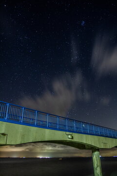 Starry night sky over Roa Island Lifeboat Station with bridge in foreground on Cumbrian Coast