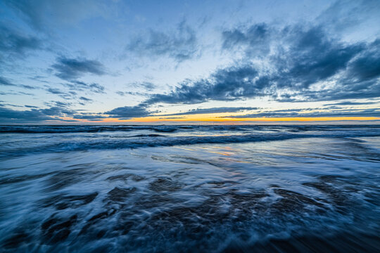 View of the Irish Sea at sunset from Sandy Gap on Walney Island in the Cumbrian Coast with rolling waves and clouds