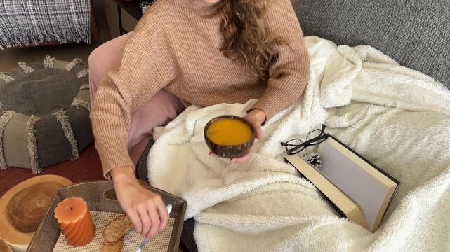 Tilt down de mujer cogiendo un cuenco de sopa en el sof&aacute;