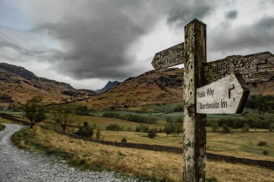 View from Little Langdale Valley towards Langdales in the English Lake District with trail signs and cloudy sky