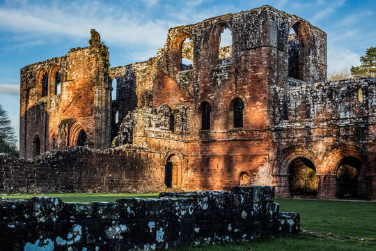 Late evening sunlight casts shadows on Furness Abbey ruins in Cumbria, UK