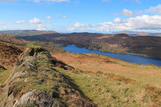 View of Coniston Water from the East in the Lake District in Cumbria, UK on a clear day with distant hills and blue sky