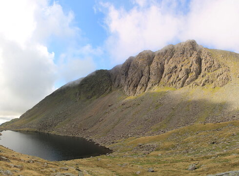 View of Goats Water under Dow Crag, a rock climbing site in the English Lake District during daylight