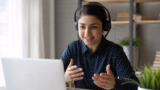 Young indian woman student with headset attending online class on laptop. Girl sitting at home during remote school lesson. Education, virtual learning, distance study and e-learning concept.