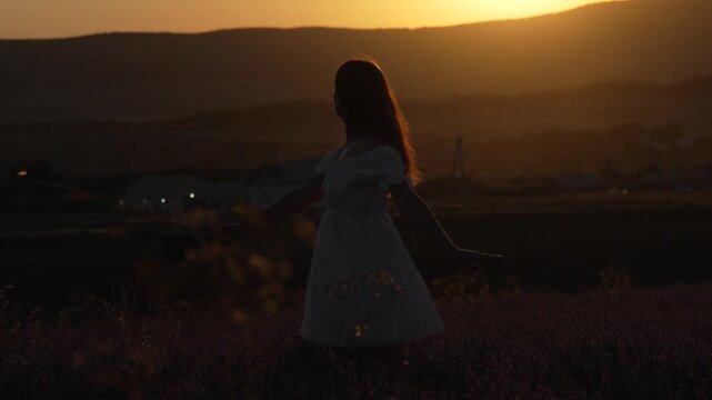 Young woman spinning happily in a vibrant lavender field at sunset. Static shot.