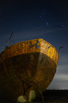View of derelict fishing trawler under starry sky on Cumbrian coast after rain