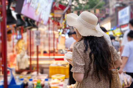 Woman in Straw Hat Wandering at Bustling Street Market