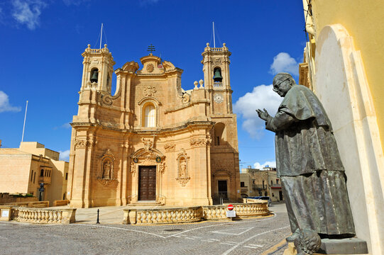 Church building in Gharb village with a statue nearby under the clear sky in Gozo Island, Malta