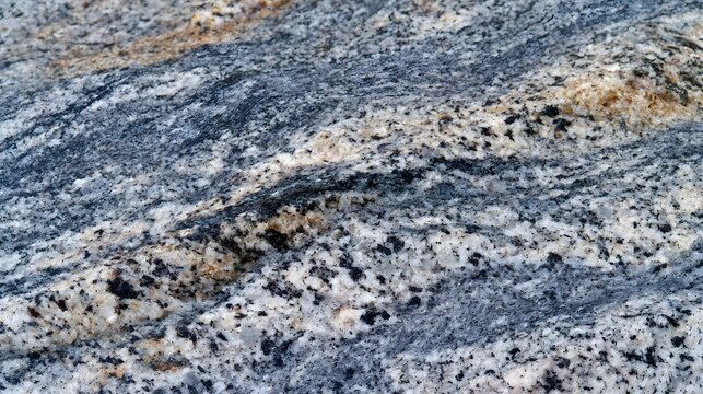 Close up of a textured gray granite surface with scattered black and white mineral grains forming natural patterns