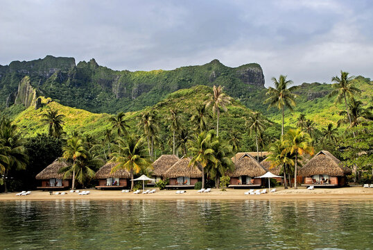 Bungalows by the beach at Moorea Pearl Resort surrounded by lush hills in French Polynesia