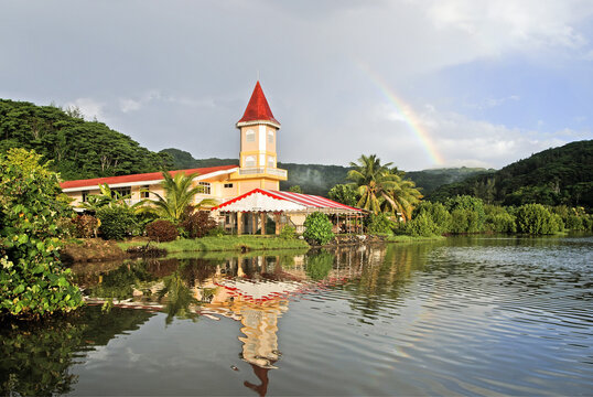 Rainbow appears above church in Uturoa on Raiatea island with calm water reflections
